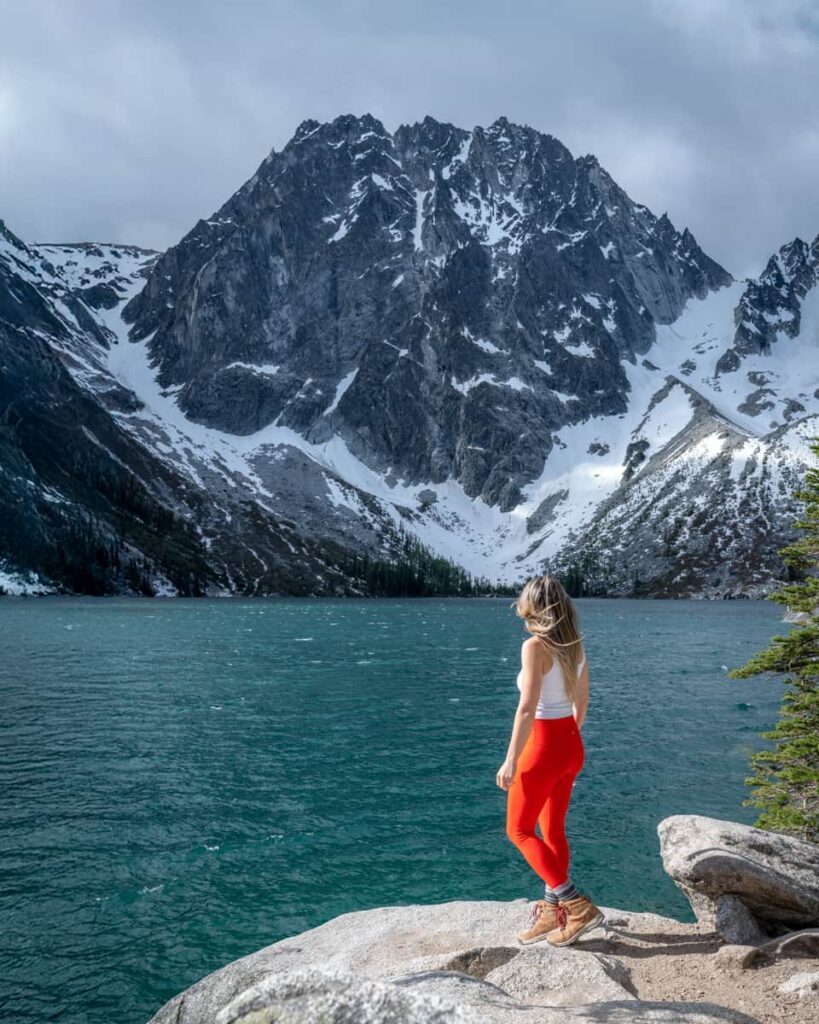 Woman standing on rock at Colchuck lake in Leavenworth Washington