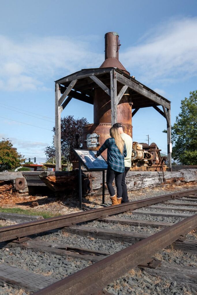 a couple standing on railroad tracks reading about a historical exhibit