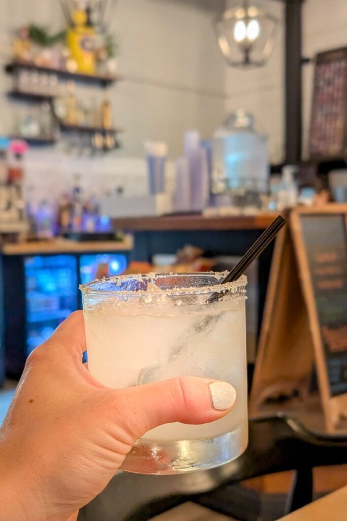 a hand holding a drink with a salted rim at moms tacos