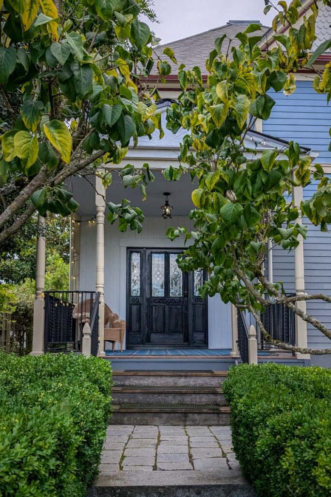 an elegant front porch shaded by lush greenery called le sorell inn