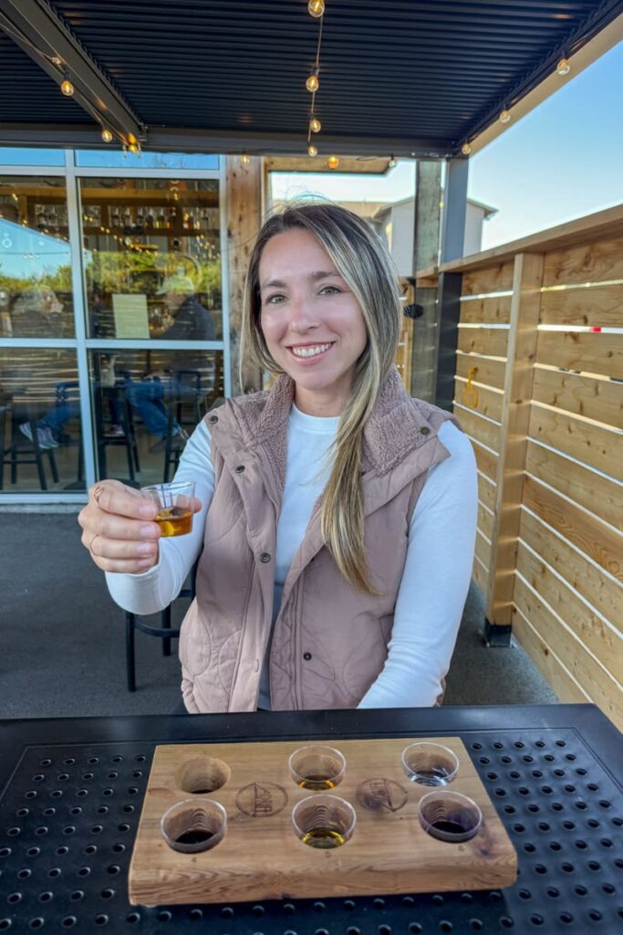 woman-smiling-with-tasting-flight-board-at-adrift-distillers