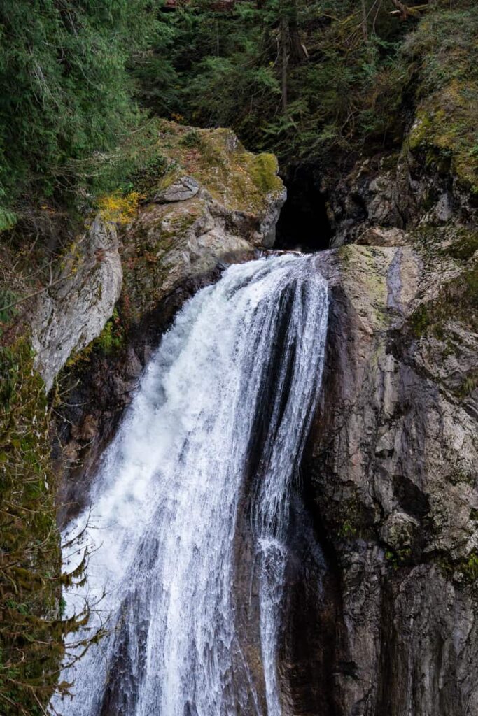 twin falls casscading from dark moss lined cavern onto rocky gorge